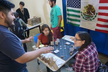 Juan Morales-Rocha observes students playing his game "Xicanx"